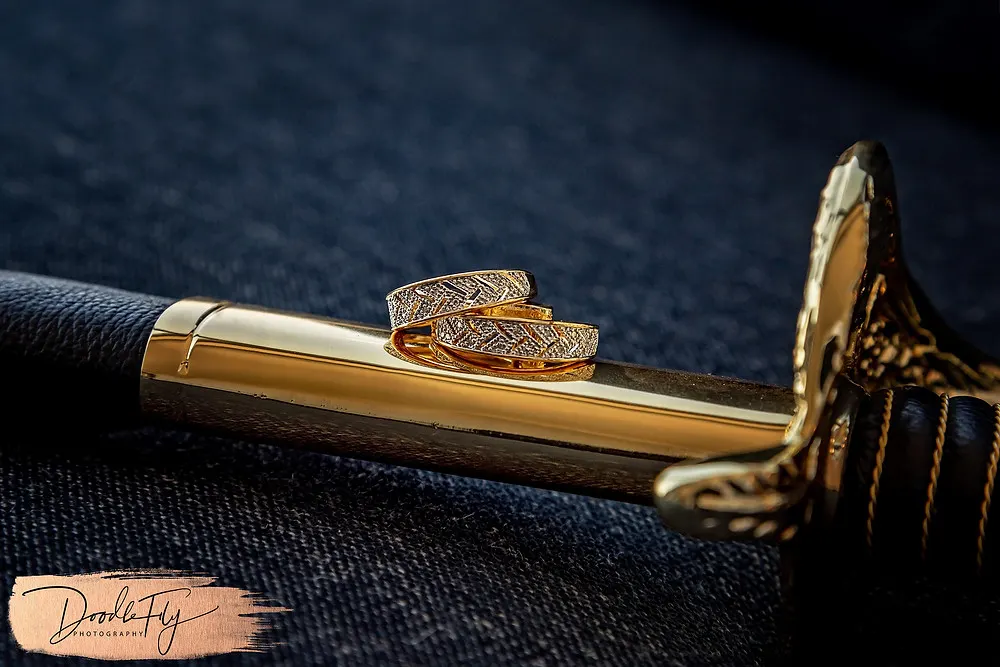 Doodle FLy Photography wedding photo of Wedding Rings Details with Navy Saber Sword for Bride and groom at Burroughs Home Venue in Fort Myers Florida